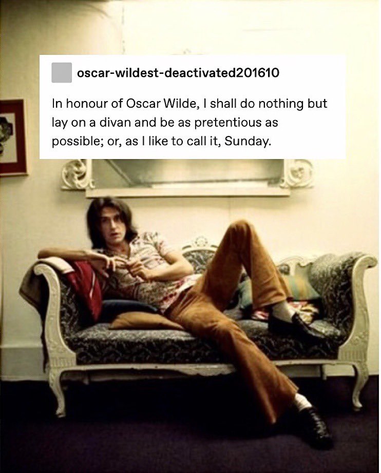 Picture of Ray Davies of The Kinks sitting on and leaning on one side of an antique couch sometime in the early 70s. On top of the photo is a screenshot of a Tumblr post that reads: In honour of Oscar Wilde, I shall do nothing but lay on a divan and be as pretentious as possible; or as I like to call it, Sunday.
